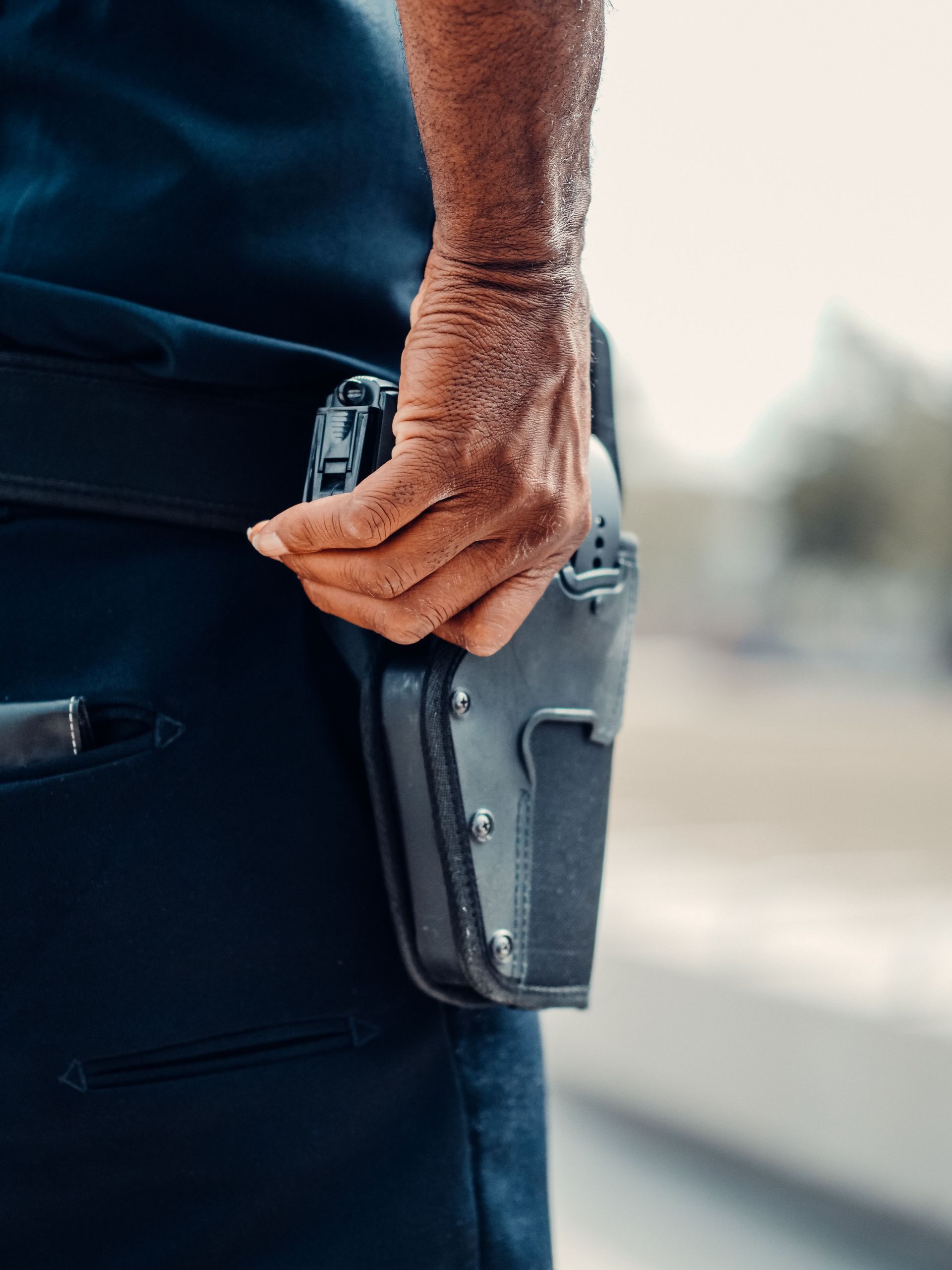 A police officer's hand gripping the holster of a handgun, symbolizing readiness and security.