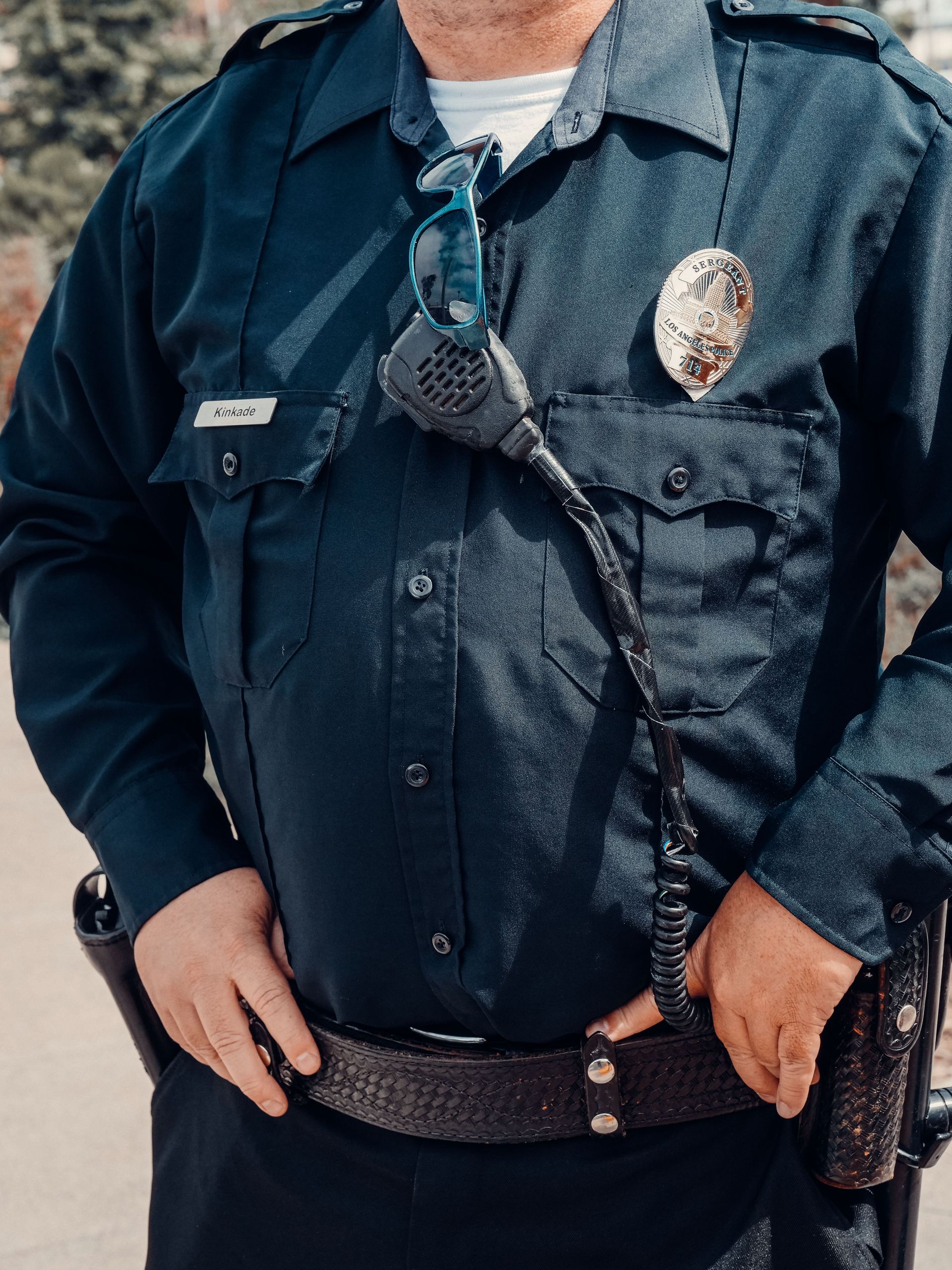 Close-up view of a police officer wearing a dark uniform with badge and radio microphone.